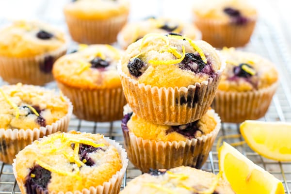 Gluten-free lemon blueberry muffins on a cooling rack topped surrounded by lemon slices.