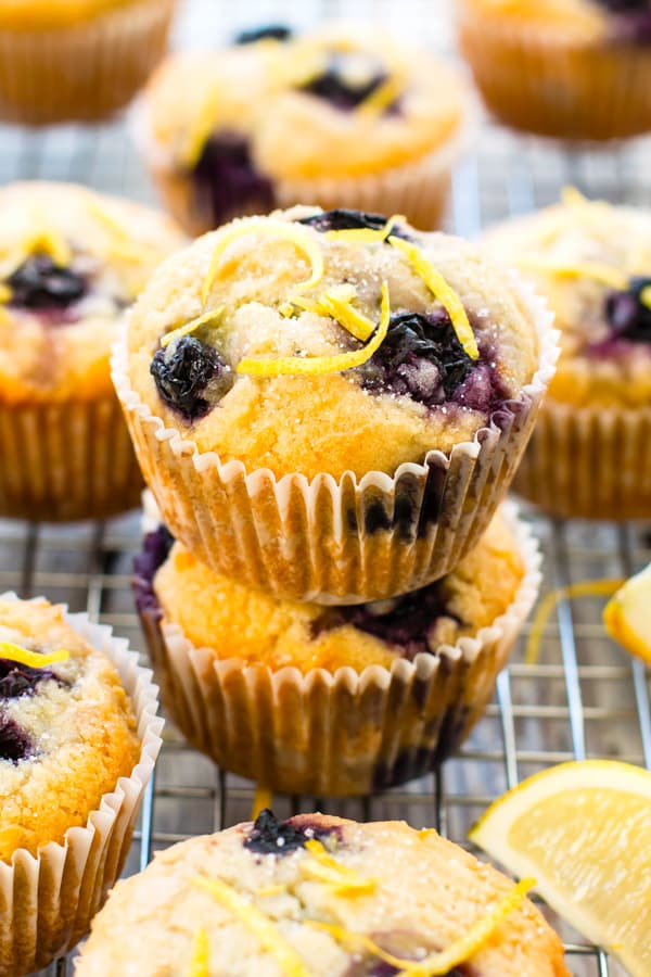 Healthy lemon muffins with blueberries stacked on top of each other on a cooling rack.
