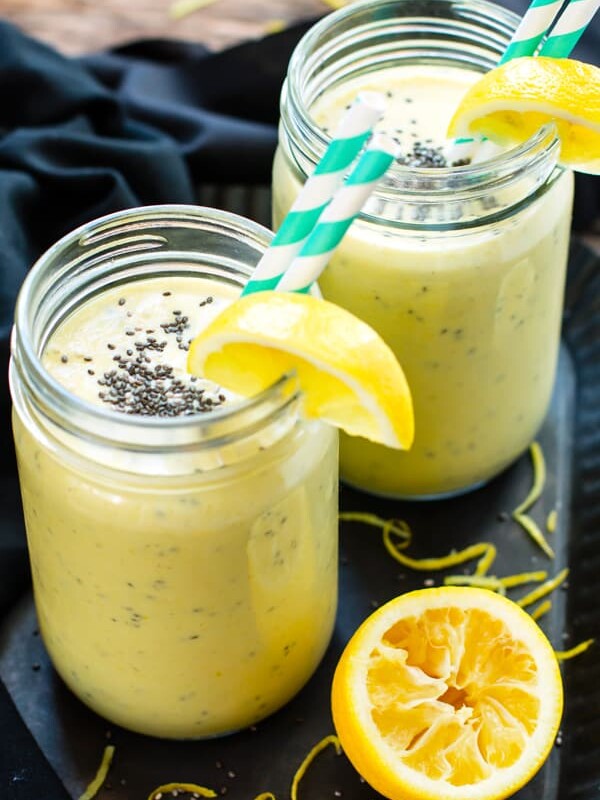 Two glasses filled with a turmeric smoothie recipe using lemon, bananas, and other fresh ingredients.