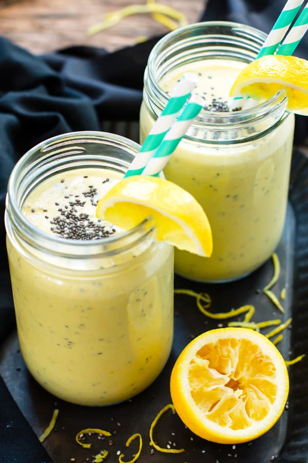 Two glasses filled with a turmeric smoothie recipe using lemon, bananas, and other fresh ingredients.