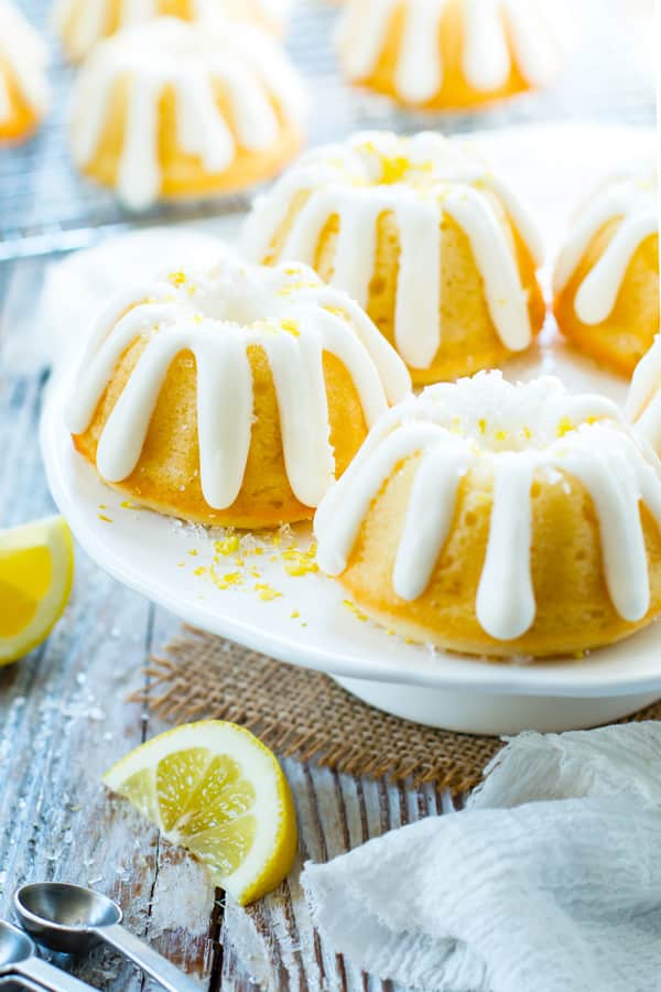 Mini Bundt Cakes with lemon and cream cheese frosting on a white cake plate.