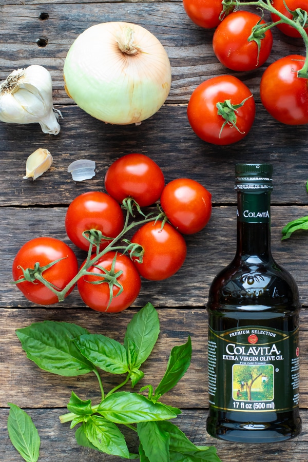 Fresh tomatoes, garlic cloves, olive oil, and fresh basil as the main ingredients in a tomato or marinara sauce.
