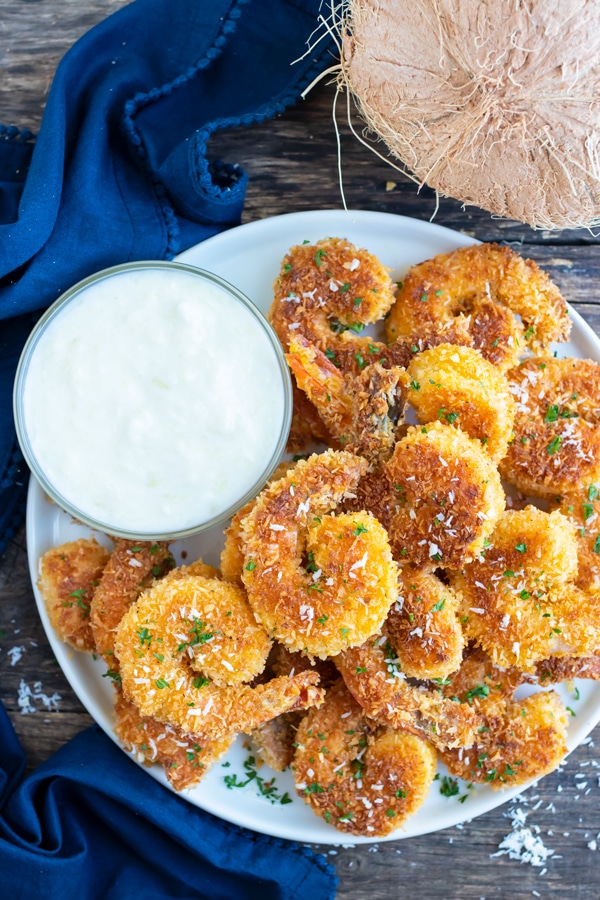 A platter full of healthy coconut fried shrimp with a creamy yogurt dipping suace.