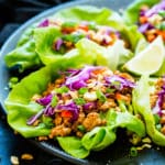 A plate full of gluten-free Ground Chicken Thai Lettuce Wraps with lime wedges for lunch.