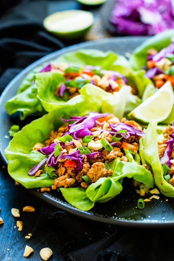 A plate full of gluten-free Ground Chicken Thai Lettuce Wraps with lime wedges for lunch.