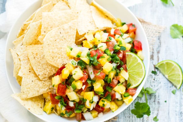 Pico de Gallo made with pineapples and lime in a bowl with tortilla chips.