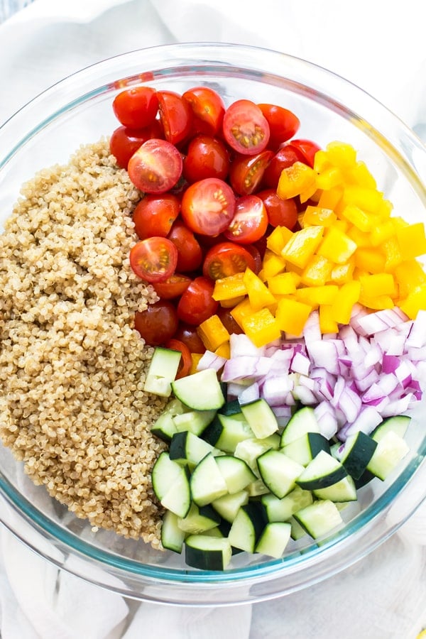 A glass bowl filled with fresh vegetables to create a Summer Vegetable Quinoa Salad.