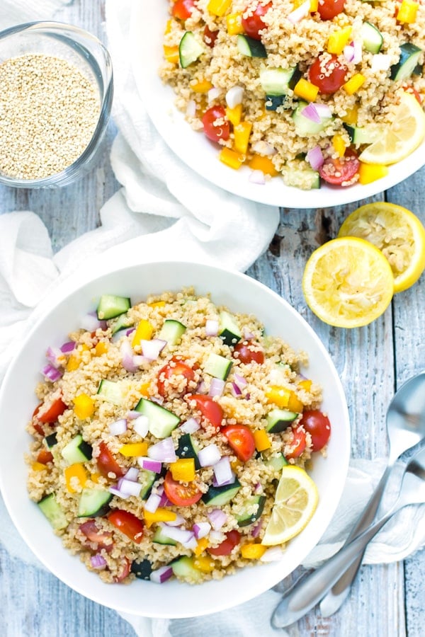 Two bowls of Summer Vegetable Quinoa Salad on a table with lemon slices.