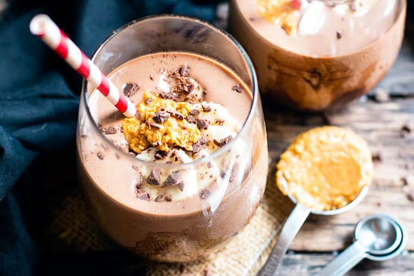 A glass filled with a gluten-free chocolate peanut butter smoothie recipe with a straw.
