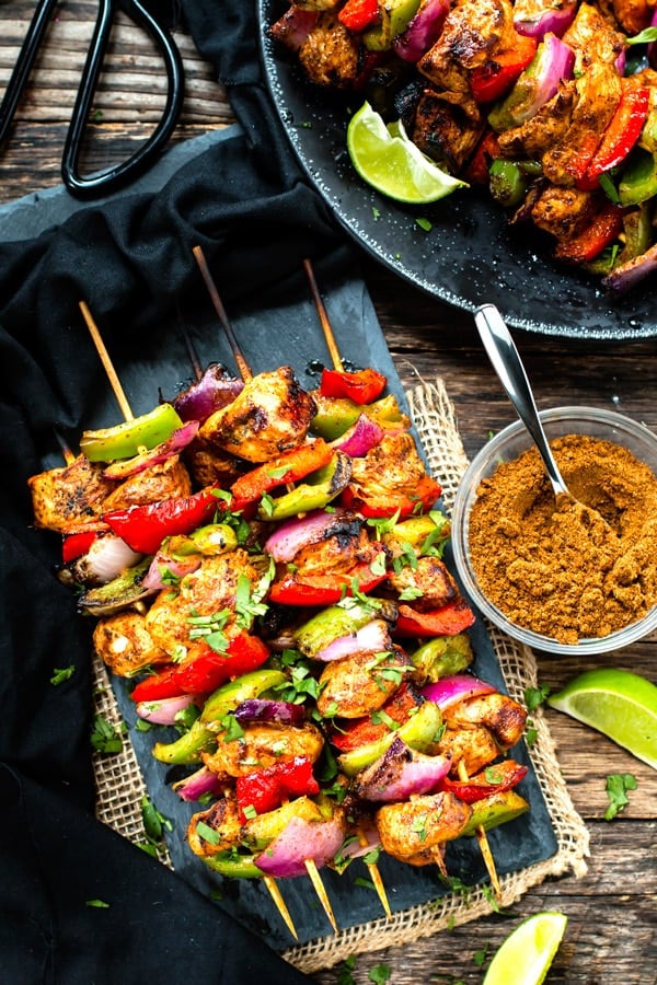 Grilled Fajita Chicken Kabob recipe on a serving slab with seasoning on the side.