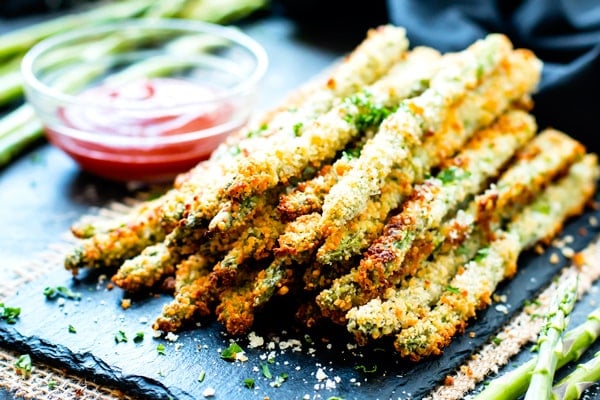A stack of gluten-free baked asparagus fries on a blue slab ready to serve.