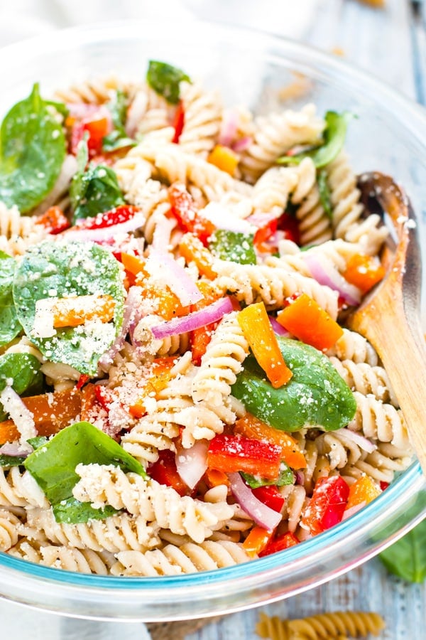 Easy pasta salad in a bowl with fresh basil and tomatoes for a summer lunch.