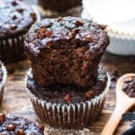 A picture of bitten chocolate banana muffins recipe on a wooden table.