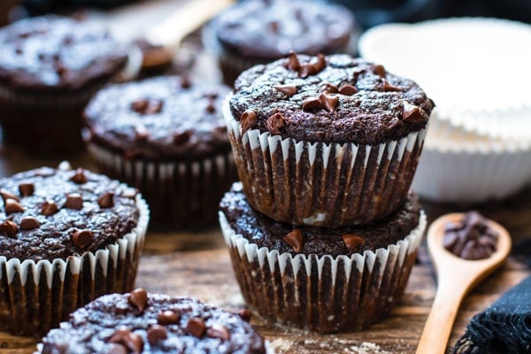 Gluten-free almond flour muffins in a stack surrounded by other muffins on a table.