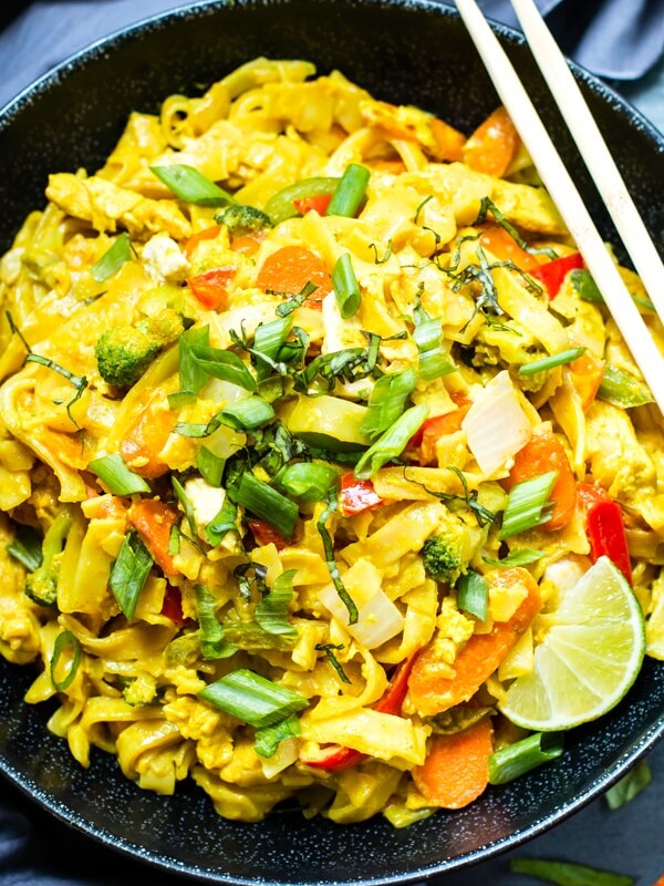 An overhead picture of Golden Thai Curry Noodles in a bowl with lime slices and chopsticks.