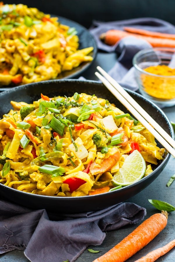 Two bowls filled with gluten-free curry rice noodles with chopsticks on the side.