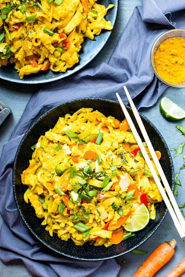 Golden Thai Curry Noodles in two bowls on a blue table for a healthy dinner.