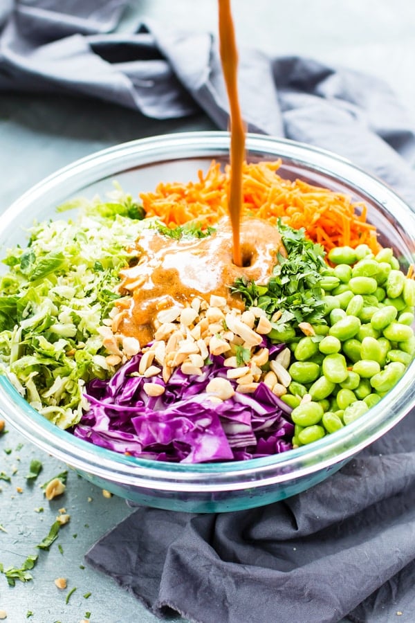 Almond butter dressing poured into a bowl of gluten-free vegan salad for lunch.