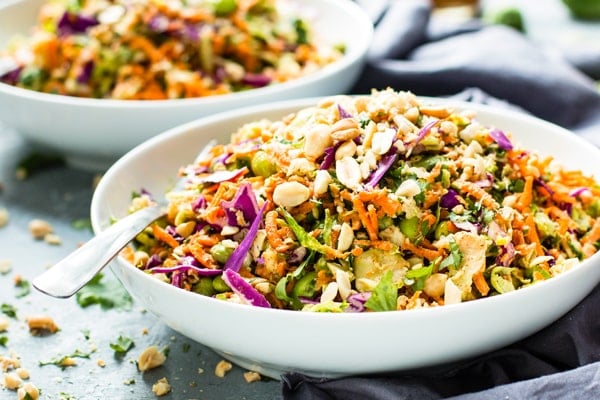 Two white bowls filled with Thai-Style Shredded Brussels Sprouts Salad for dinner.