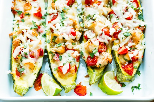 Cilantro Lime Chicken Stuffed Zucchini Boats in a casserole dish surrounded by lime wedges for an easy dinner.