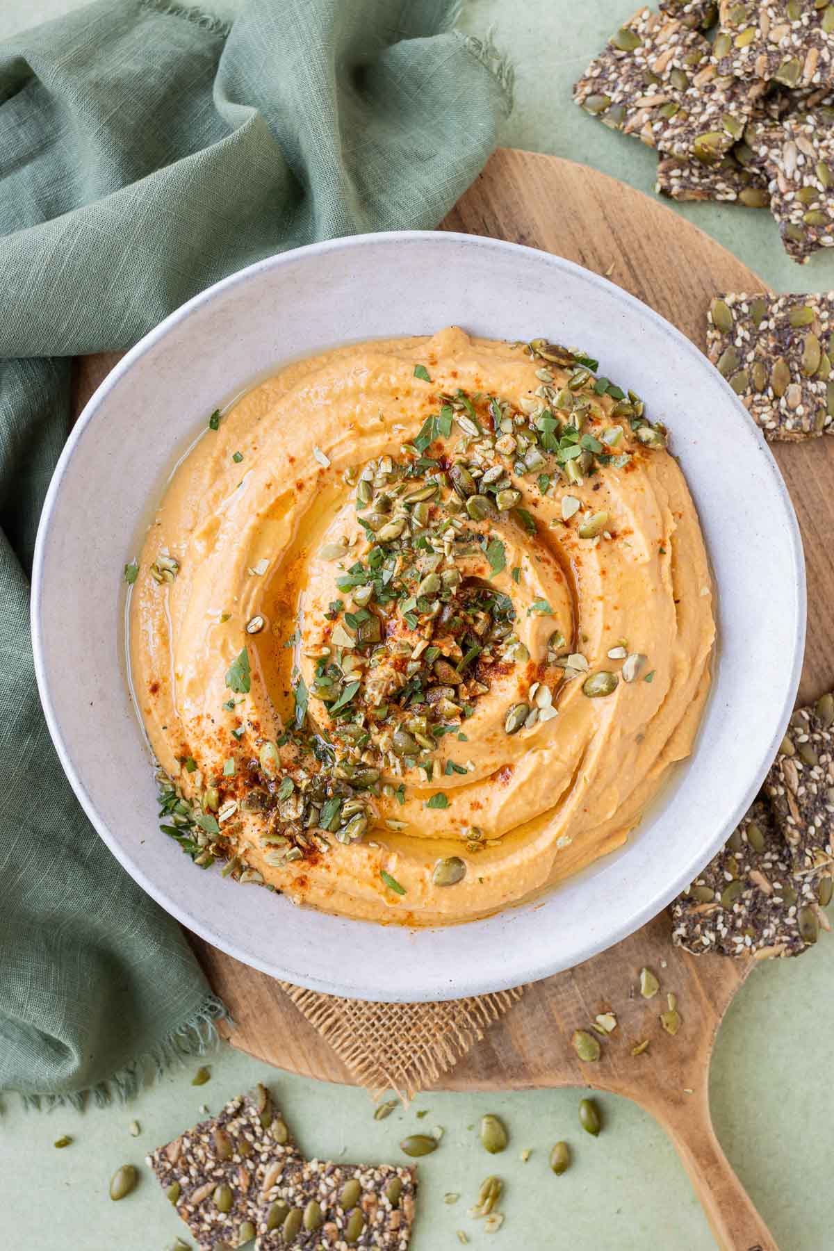 A creamy pumpkin hummus recipe is served in a white bowl.