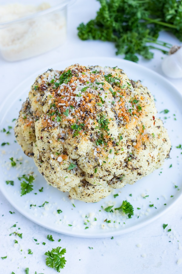 Top baked cauliflower head with fresh parley before serving this quick and easy side dish.