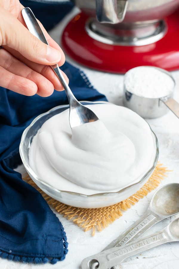 A silver spoon cooping out a tablespoon of whipped cream.