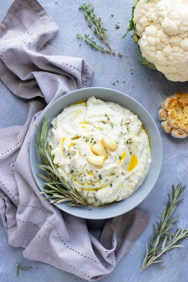 The best mashed cauliflower recipe that is topped with olive oil, garlic, and herbs.