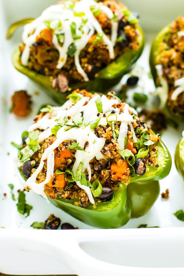 Two quinoa stuffed bell peppers in a casserole dish for dinner.