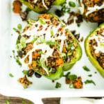 Vegan stuffed peppers recipe with black bean and quinoa on a white serving tray.