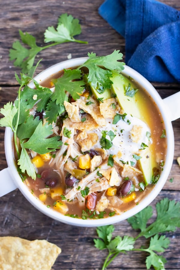 Crock-Pot chicken tortilla soup with fresh cilantro, sliced avocados, and sour cream on top.