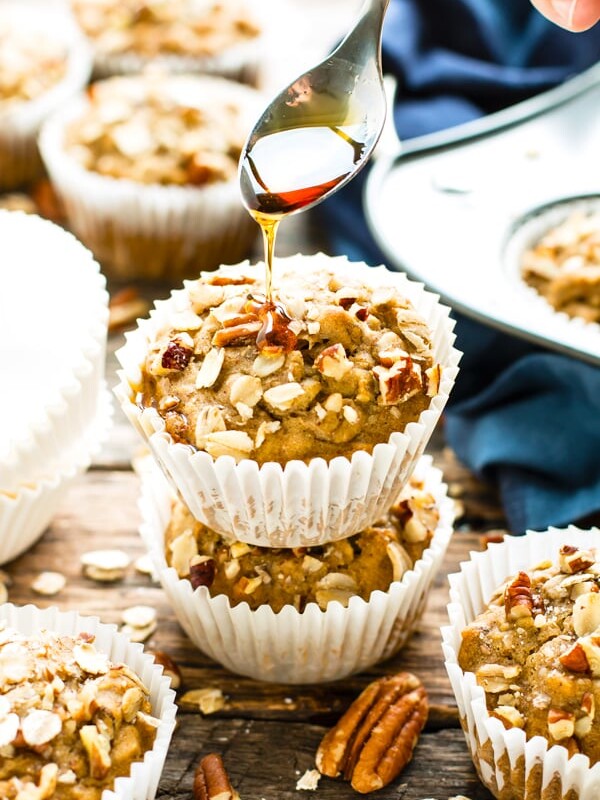 Gluten-free oat muffins in a pile with syrup being drizzled on top.