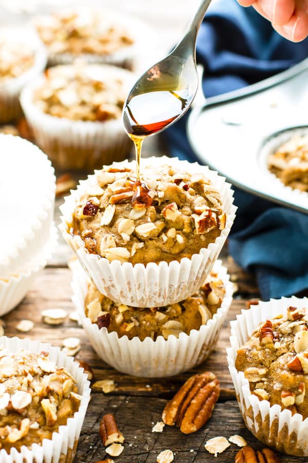 Gluten-free oat muffins in a pile with syrup being drizzled on top.