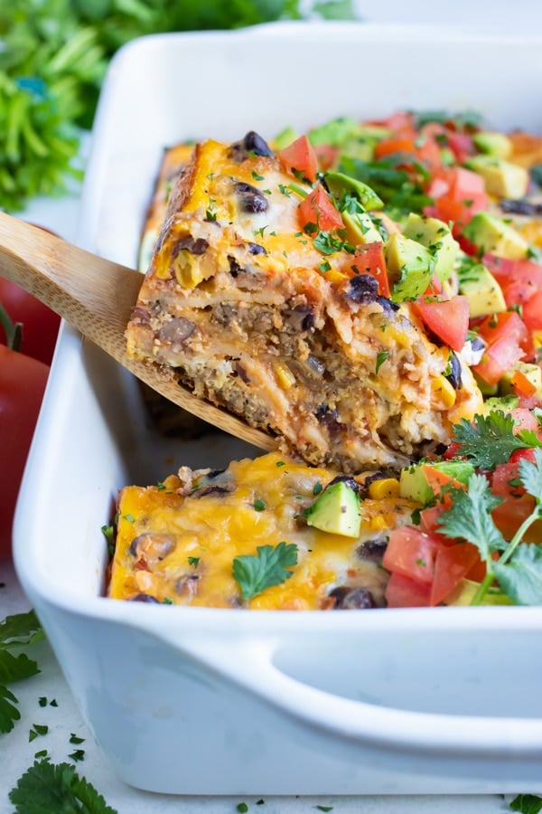 Mexican breakfast casserole is served with a wooden spoon.