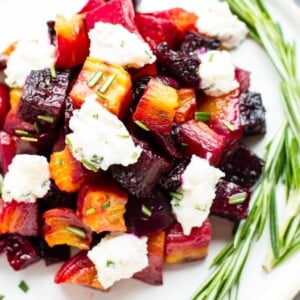 An overhead picture of gluten-free Oven-Roasted Beets on a white plate with fresh herbs.