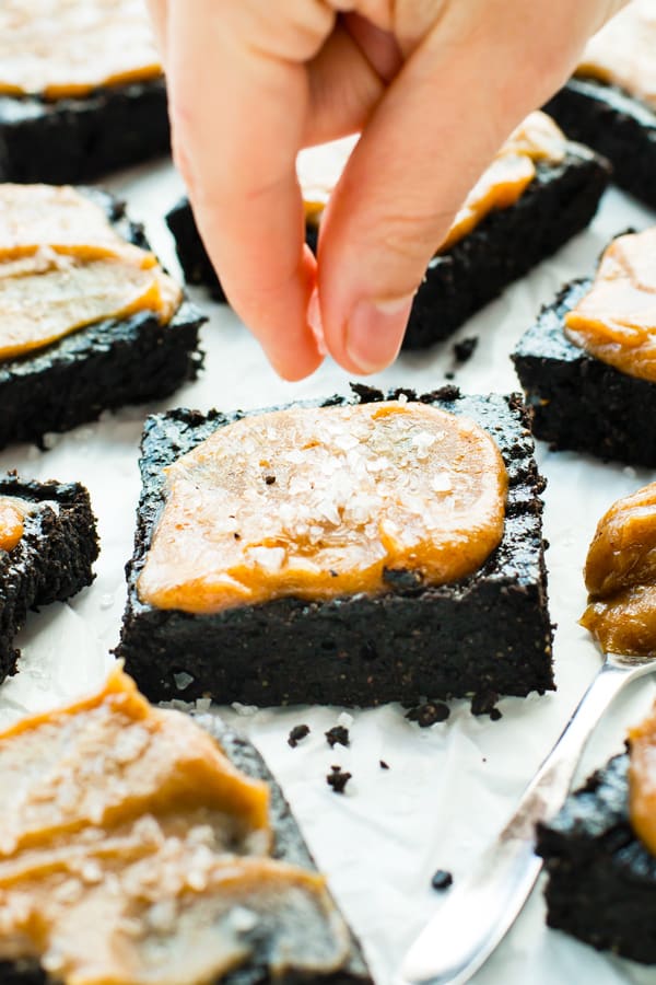 Two fingers sprinkling a topping on this paleo brownie recipe.