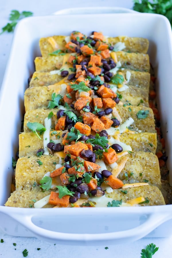 Enchiladas are served from a white baking dish.