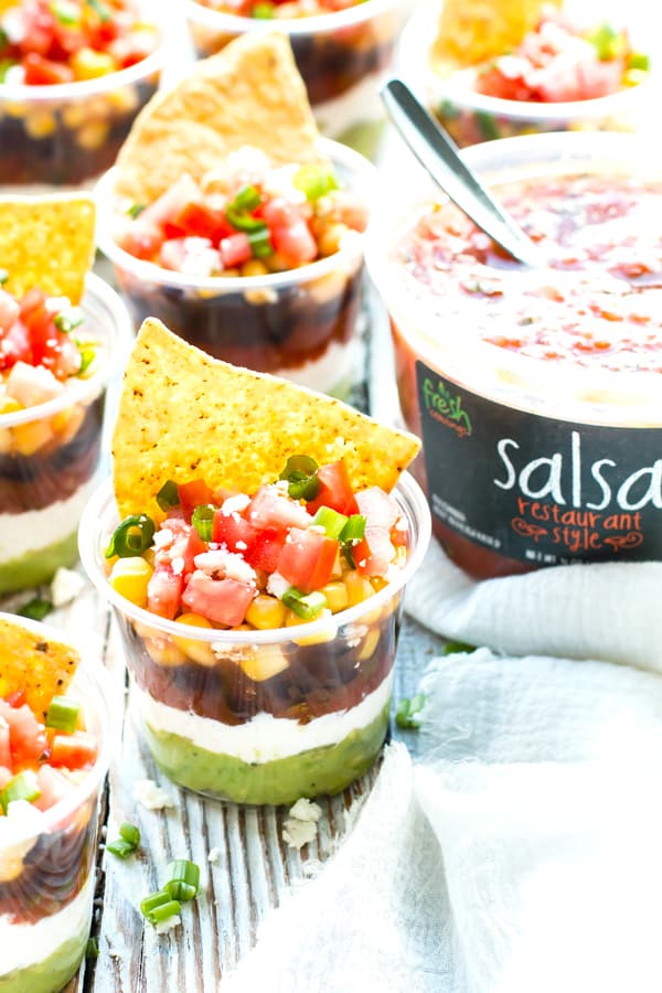 A picture of Fresh Cravings salsa with individual plastic cups filled with a healthy 7-layer dip.