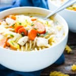 A white bowl filled with easy chicken and noodles as a soup for a healthy lunch.