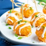 Buffalo chicken meatballs with a drizzle of ranch dressing on an appetizer plate.