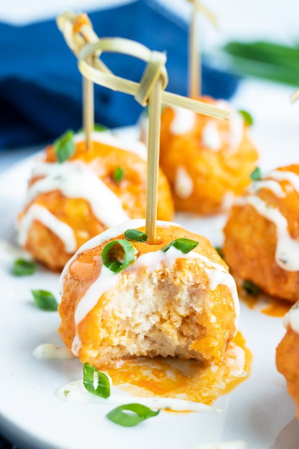 A close-up of a low-carb buffalo chicken meatballs with a bite taken out.