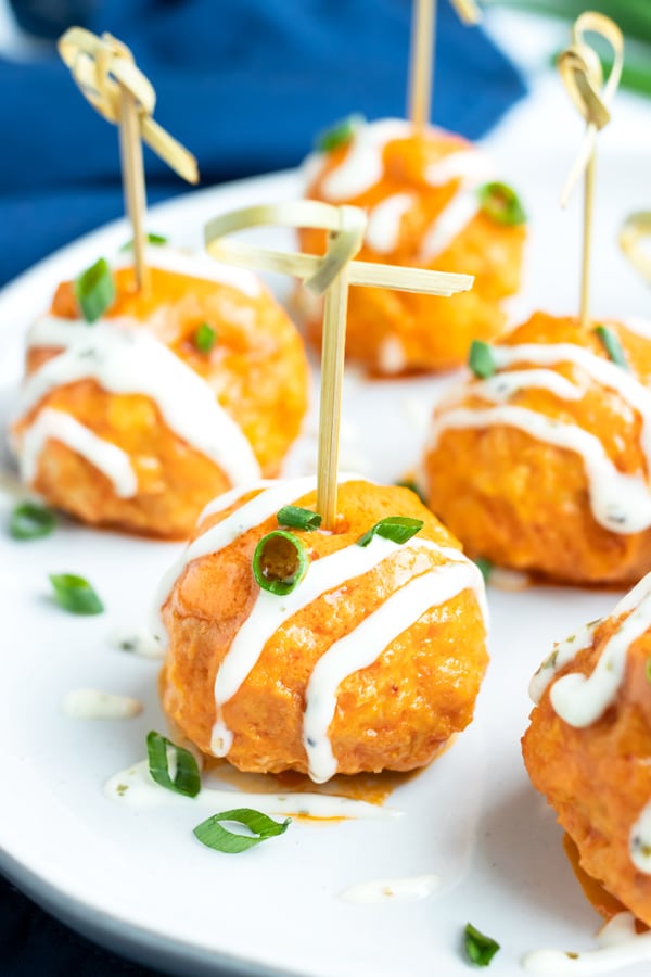 Buffalo chicken meatballs with a drizzle of ranch dressing on an appetizer plate.