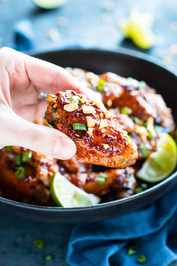 A hand holding one Sweet and Spicy Baked Thai Chicken Wing for an easy dinner.