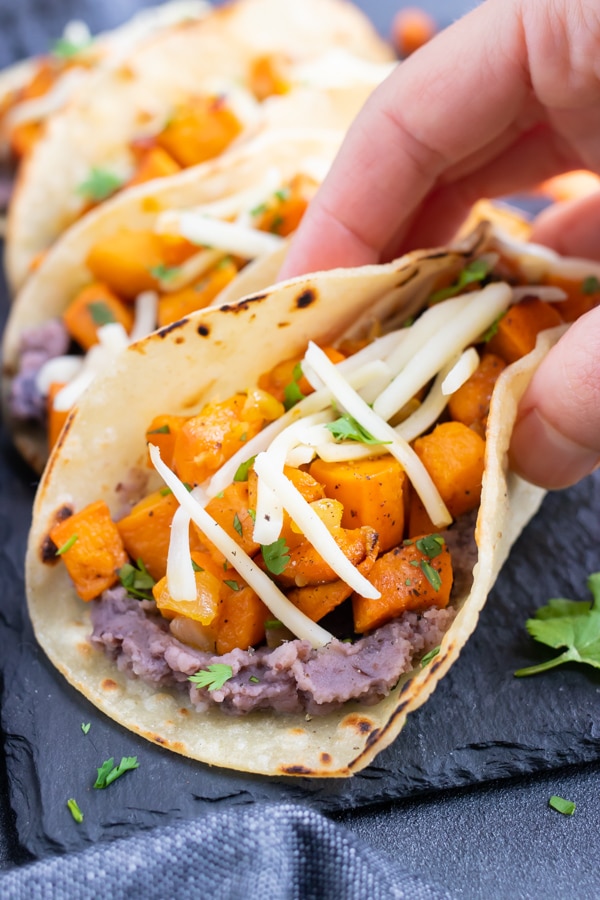 A hand holding a gluten-free and vegetarian taco that is meatless.
