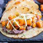 Vegetarian black bean tacos with cubed sweet potatoes in a row.