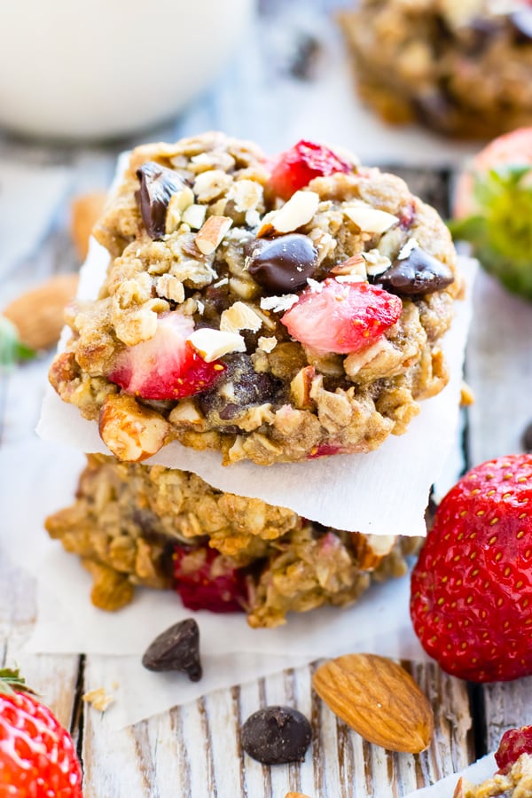 A stack of healthy oatmeal cookies with chocolate chips and strawberries on a table.