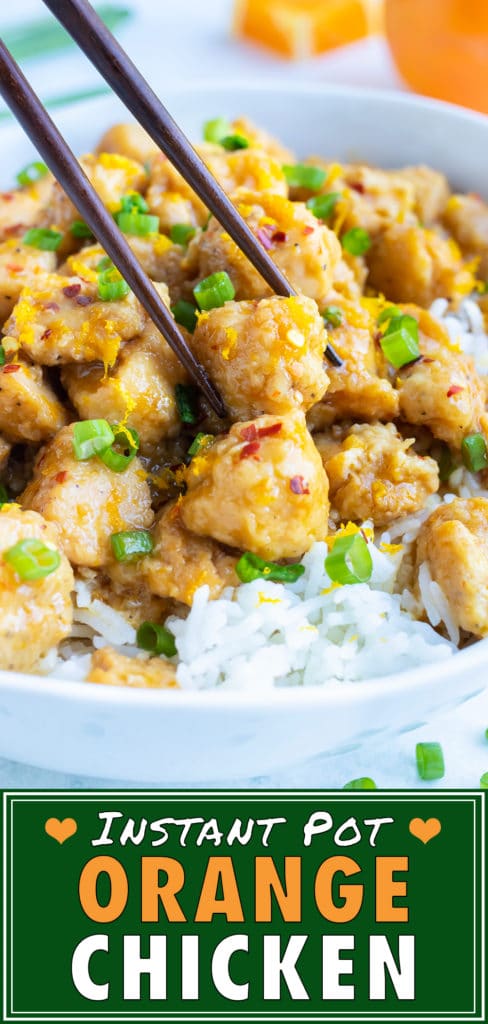 Chopsticks picking up a cube of orange chicken from a plate.