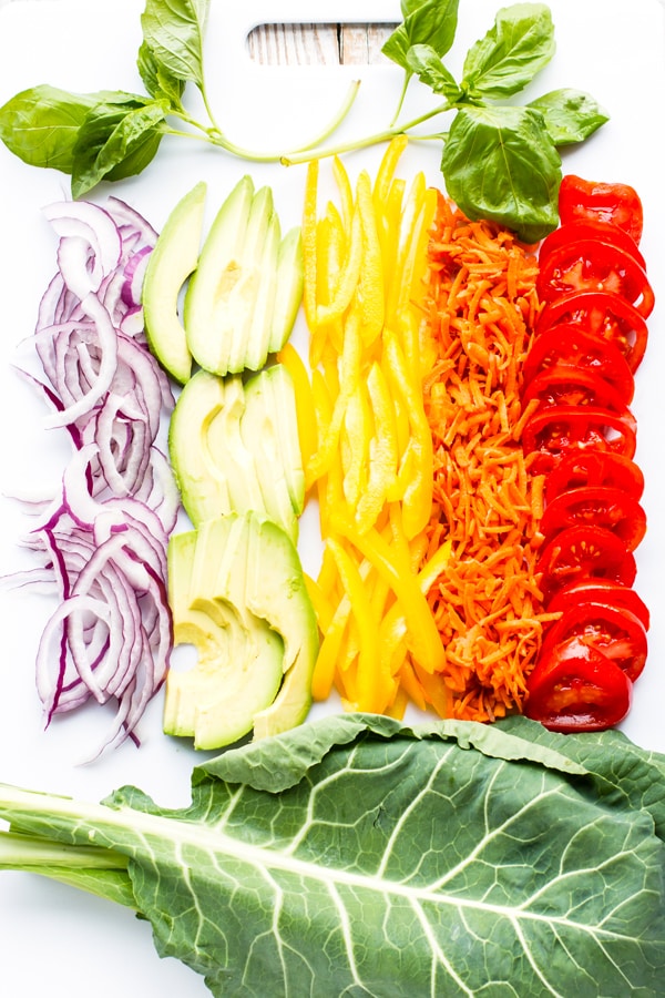 A spread of raw vegetables on a plate to make Rainbow Raw Veggie Hummus Wraps.
