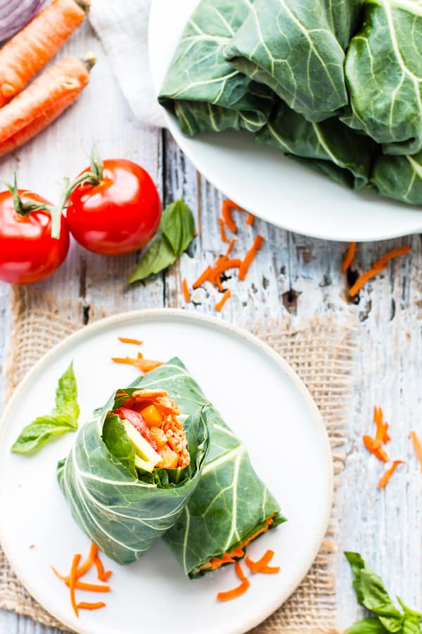 Gluten-free vegan wraps made with raw veggies and hummus on a white plate.