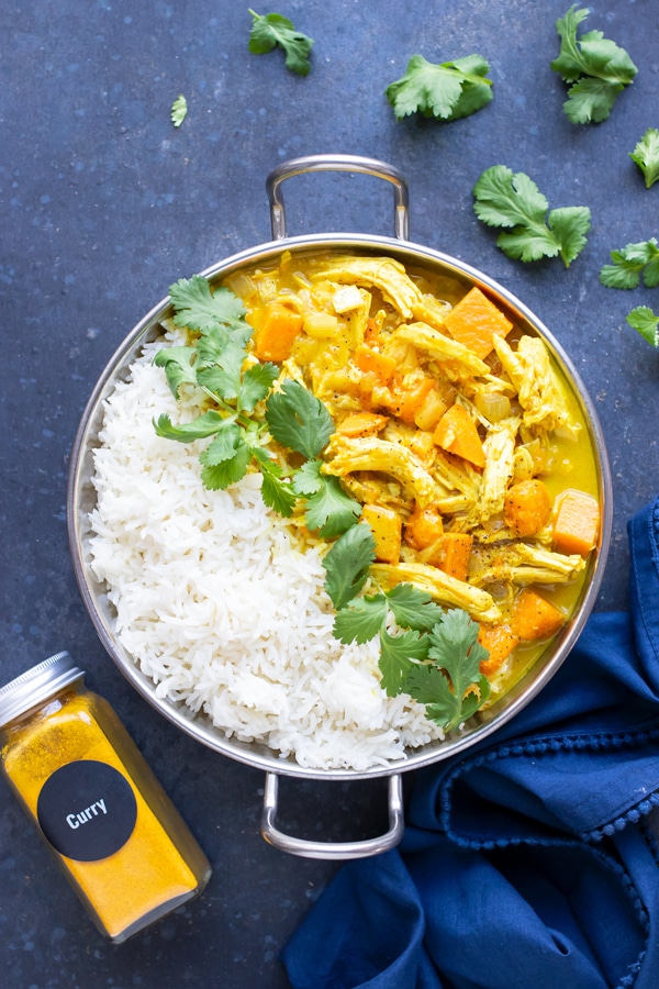 An easy chicken curry recipe with a yellow curry sauce that was made in the slow cooker and served with white rice and cilantro.